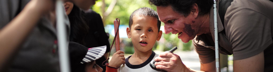 Photo of Daniel Kish teaching FLashSonar to a young Thai Boy.