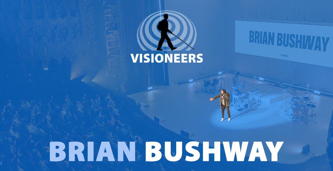 Brian Bushway. Photo of Brian on-stage at a large theater speaking to an audience.